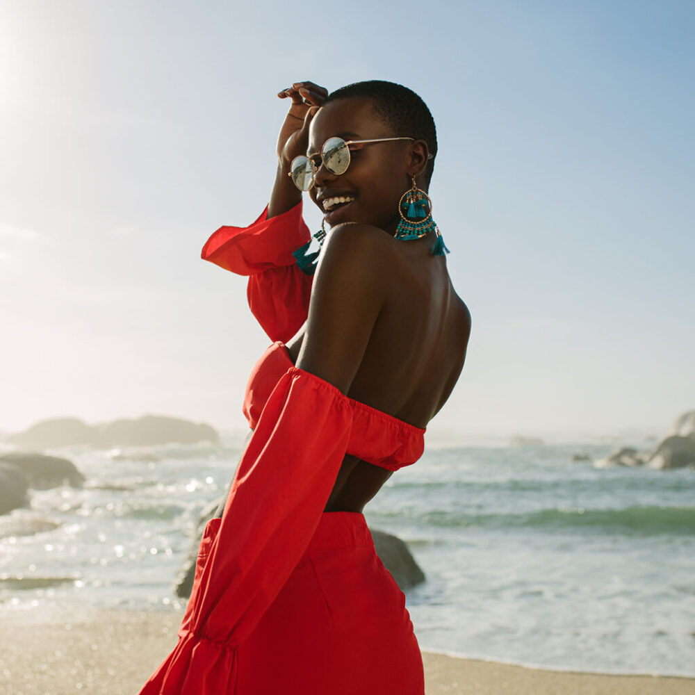 Beautiful african woman in red dress enjoying on the beach